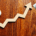 Arrow pointing up next to calculator and hundred dollar bills