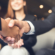 client and agent shake hands with client's female partner blurred out in bg