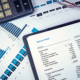 Balance sheet with financial charts and a calculator on a desk, symbolizing analysis of assets, liabilities, and equity.